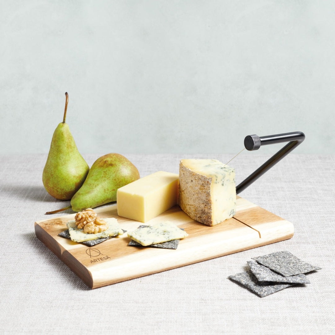 cheese and pears being sliced on a wooden serving board