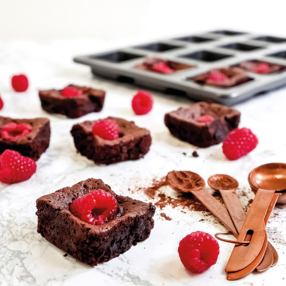 brownies with raspberry topping on table with measuring spoons