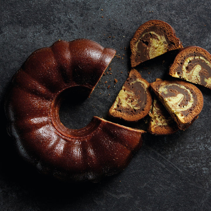 ring shaped marbled chocolate cake on slate surface cut into slices